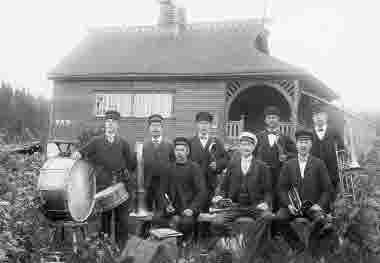 Orkester, gruppbild framför skyttepaviljongen. Karlsviks sågverk 1881-1963, Alnö. Skyttebanan och paviljongen byggdes 1900-1901 på bolagsmark ovan för skolan. Bolaget skänkte virke till byggnaden enligt styrelseprotokoll 27 juni 1900.