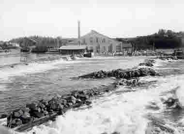 Träsliperiet, exteriör från NV med del av forsen och dammen i förgrunden 1915. Matfors träsliperi 1894-1974. 