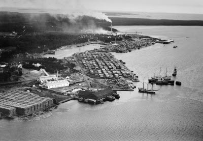 Flygfoto över Munksunds sågverk 1935. Sågen och brädgården i förgrunden,  sulfatfabriken syns i bakgrunden. Munksunds sågverk startade 1861