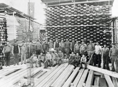 Personal, gruppbild på stabbläggare med putor, och pinnpojkar i brädgården 1904. Obbola sågverk